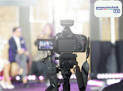 Two cameras in the foreground on tripods are filming a discussion round.